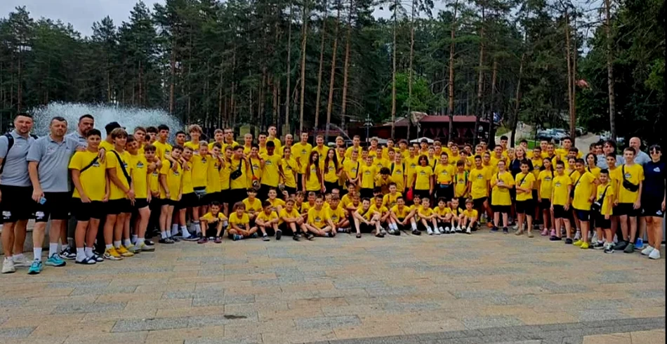 Velika grupa sportista u žutim klupskim majicama na zajedničkoj fotografiji na otvorenom