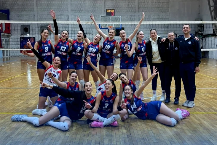 Odbojkašice u plavo-crvenim dresovima sa članovima stručnog tima pored mreže u sportskoj dvorani